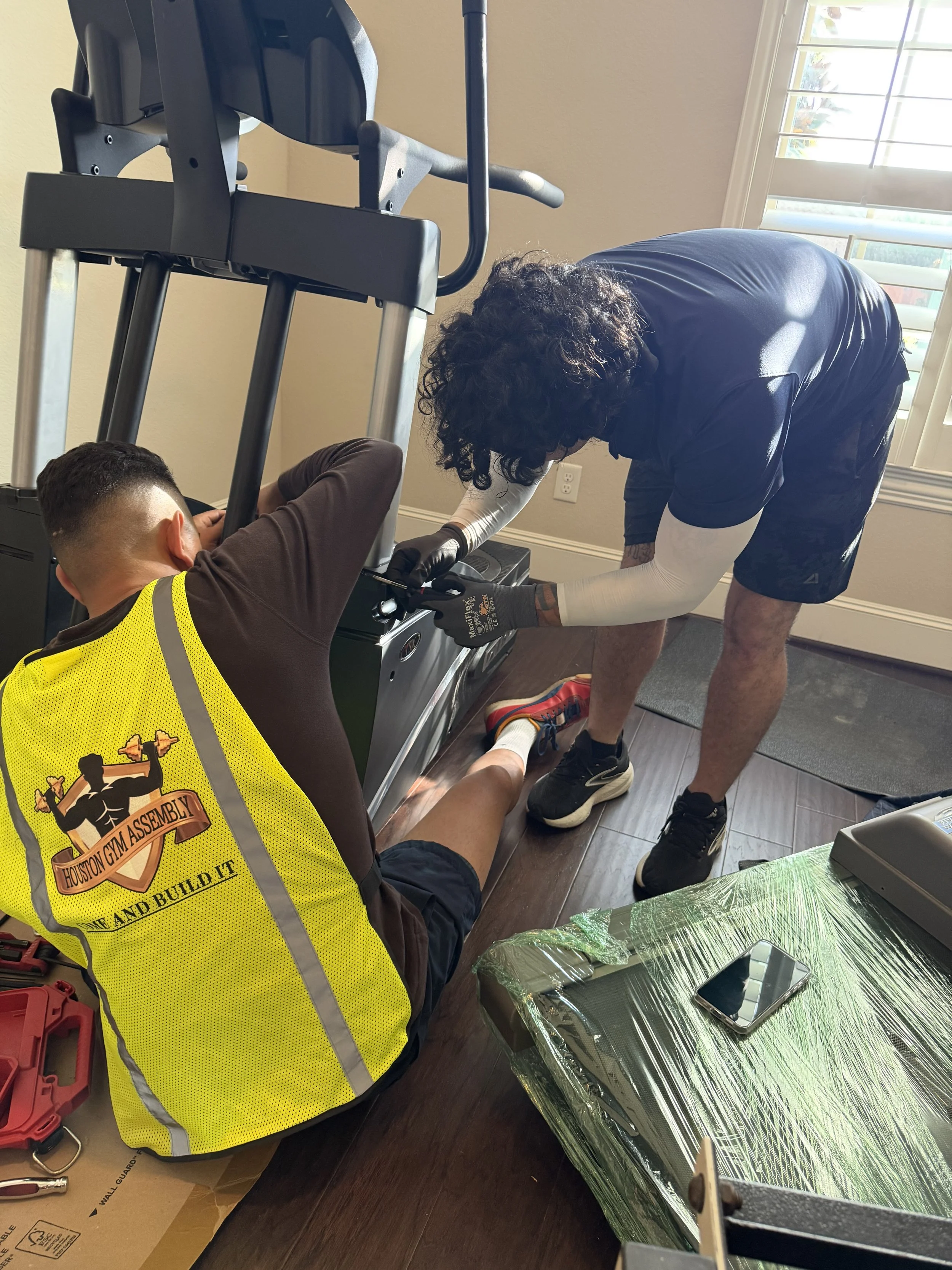 Fitness equipment technicians assembling gym equipment inside a home.