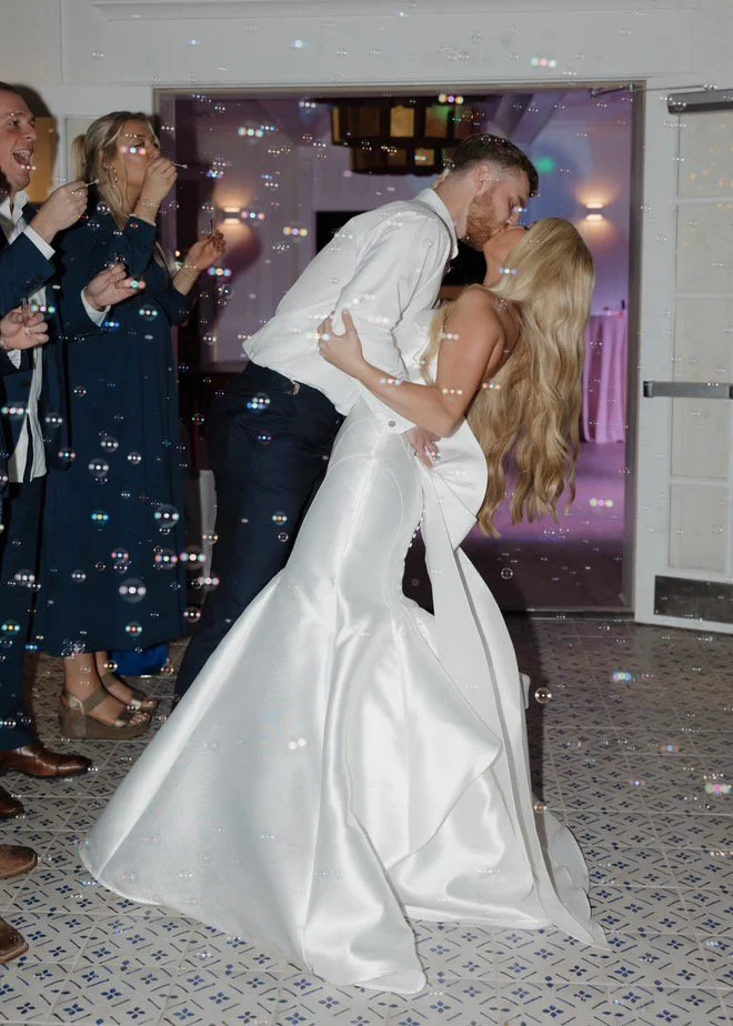 Bride and groom kissing surrounded by bubbles at a wedding reception.