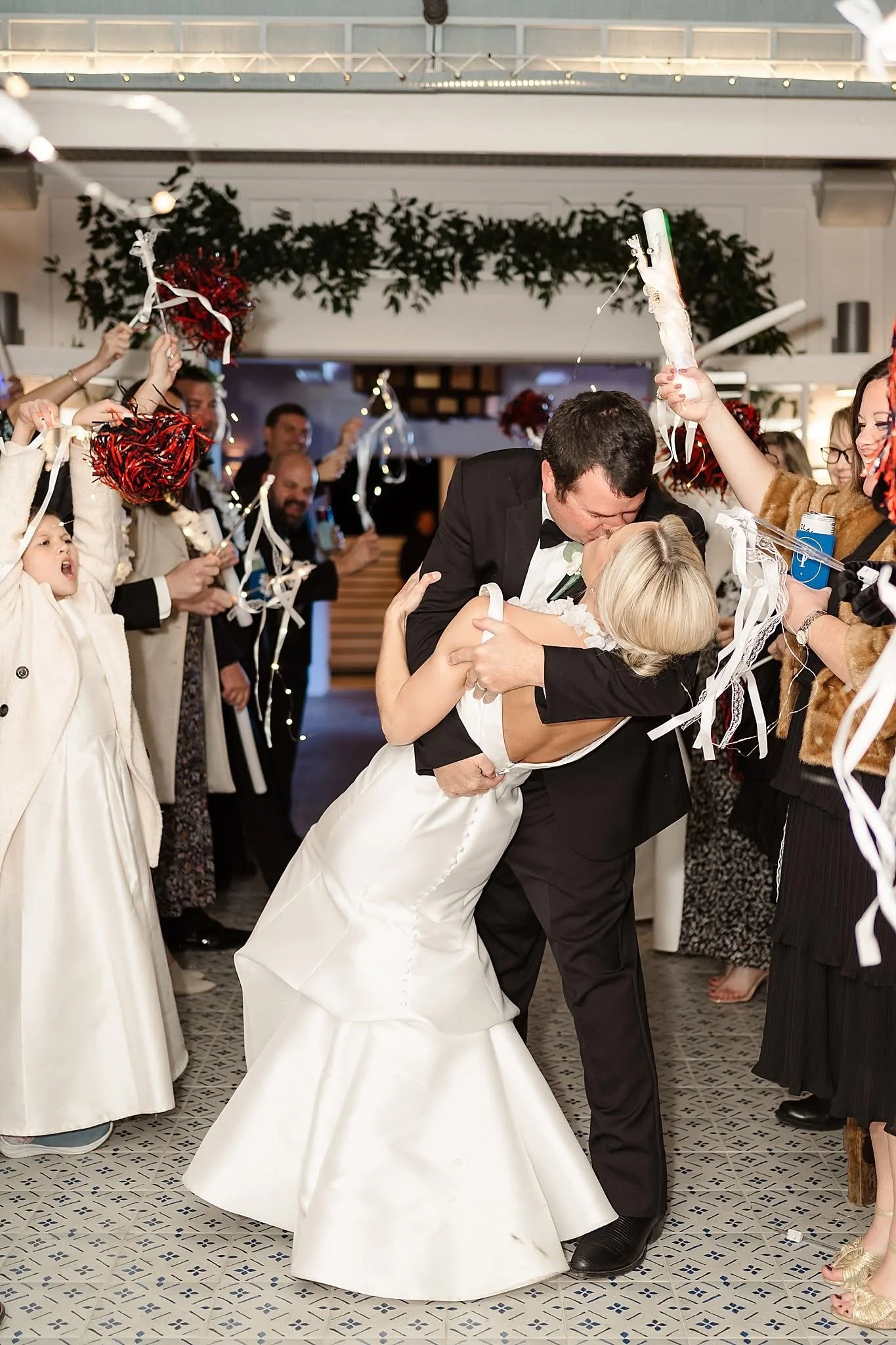Bride and groom kissing at wedding with guests celebrating around them.
