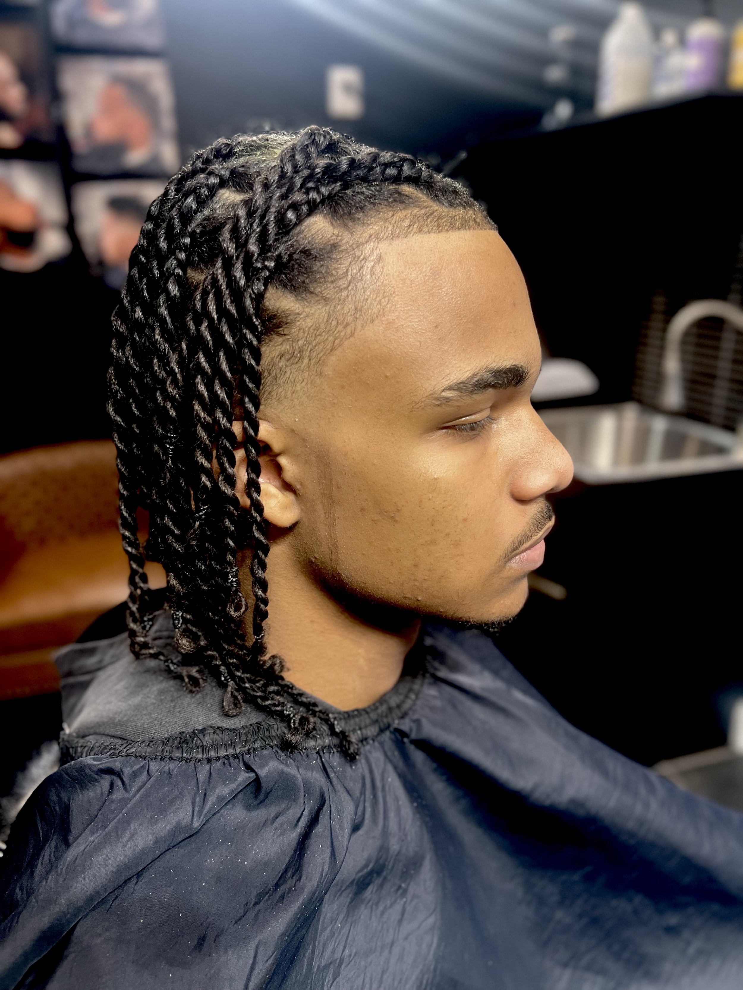 Young man with fresh twisted braids hairstyle sitting in a salon chair.