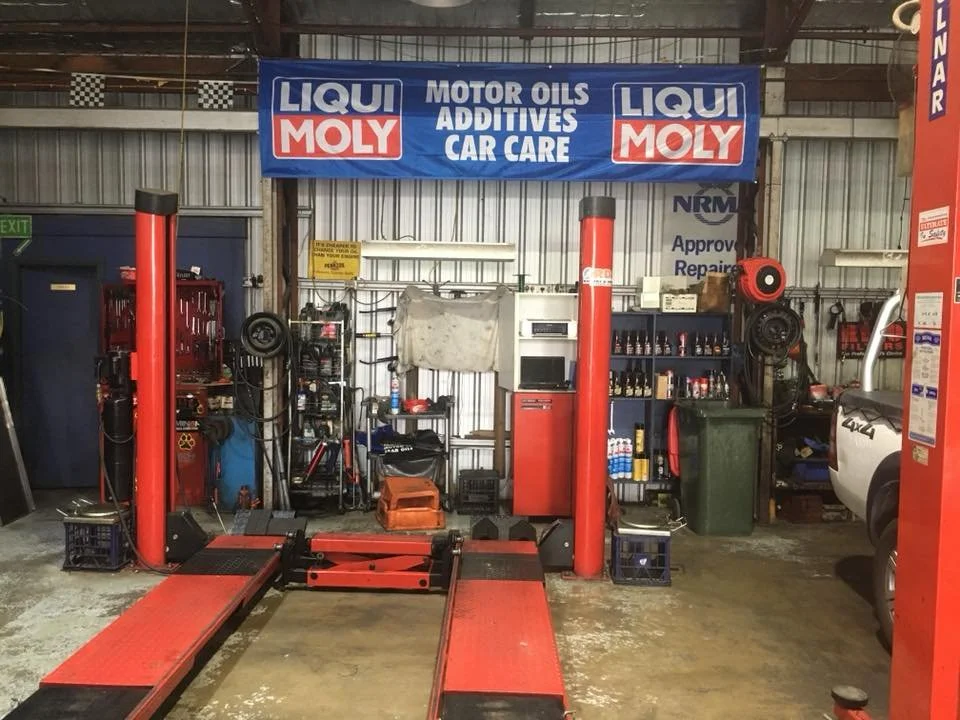 Automotive repair shop with red car lift, tools, and Liqui Moly signage