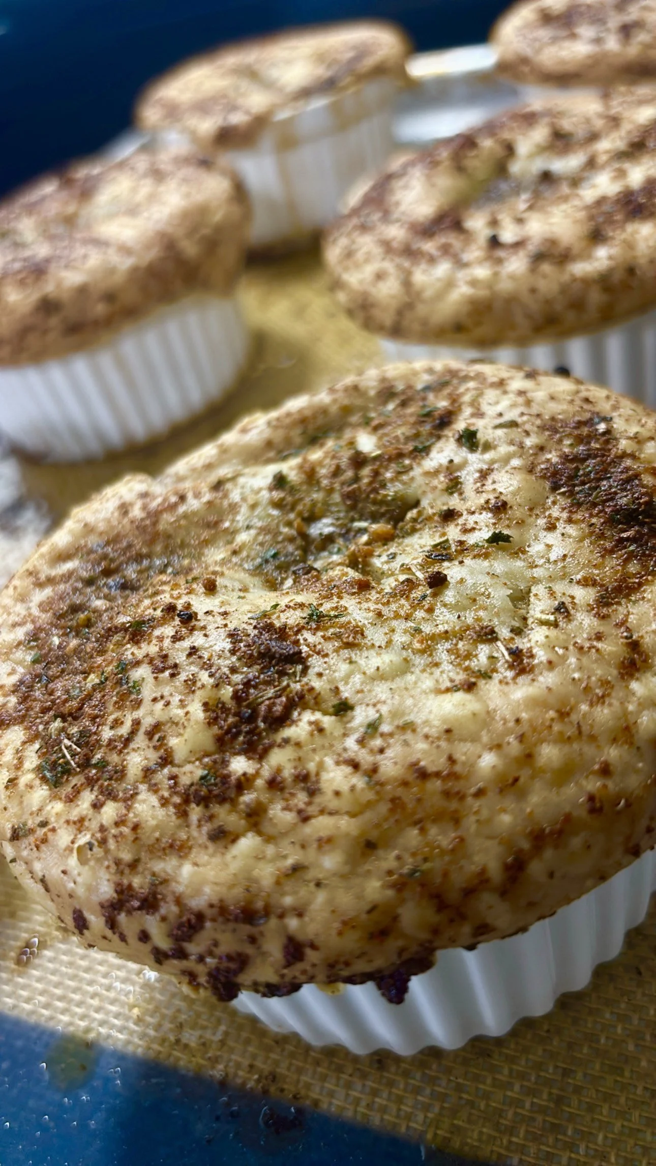 Close-up of a seasoned cooked chicken breast with herbs and spices, in a cupcake liner.