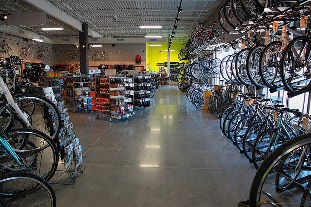 Interior of a bicycle store with bikes hanging on the right wall and on display racks on the left.