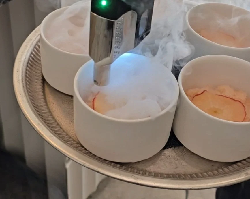 Cups with granite ice emitting vapor, containing slices of apples on a tray.