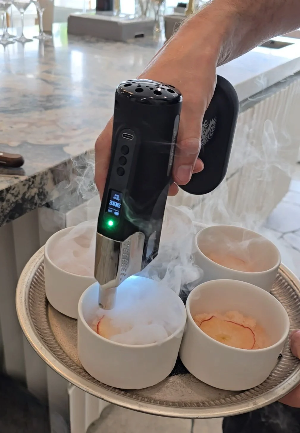 Hand using a smoke infuser on bowls containing food
