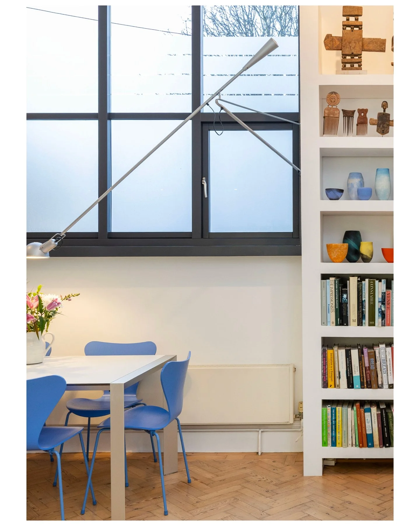 That arched window. That collection. That kitchen trolley. Swipe. &rarr;

---

Slide 1 &mdash; Dining area, blue Series 7 chairs, arched crittall window, collector's shelving
Fritz Hansen chairs, a wall of books, African sculpture, and studio ceramic