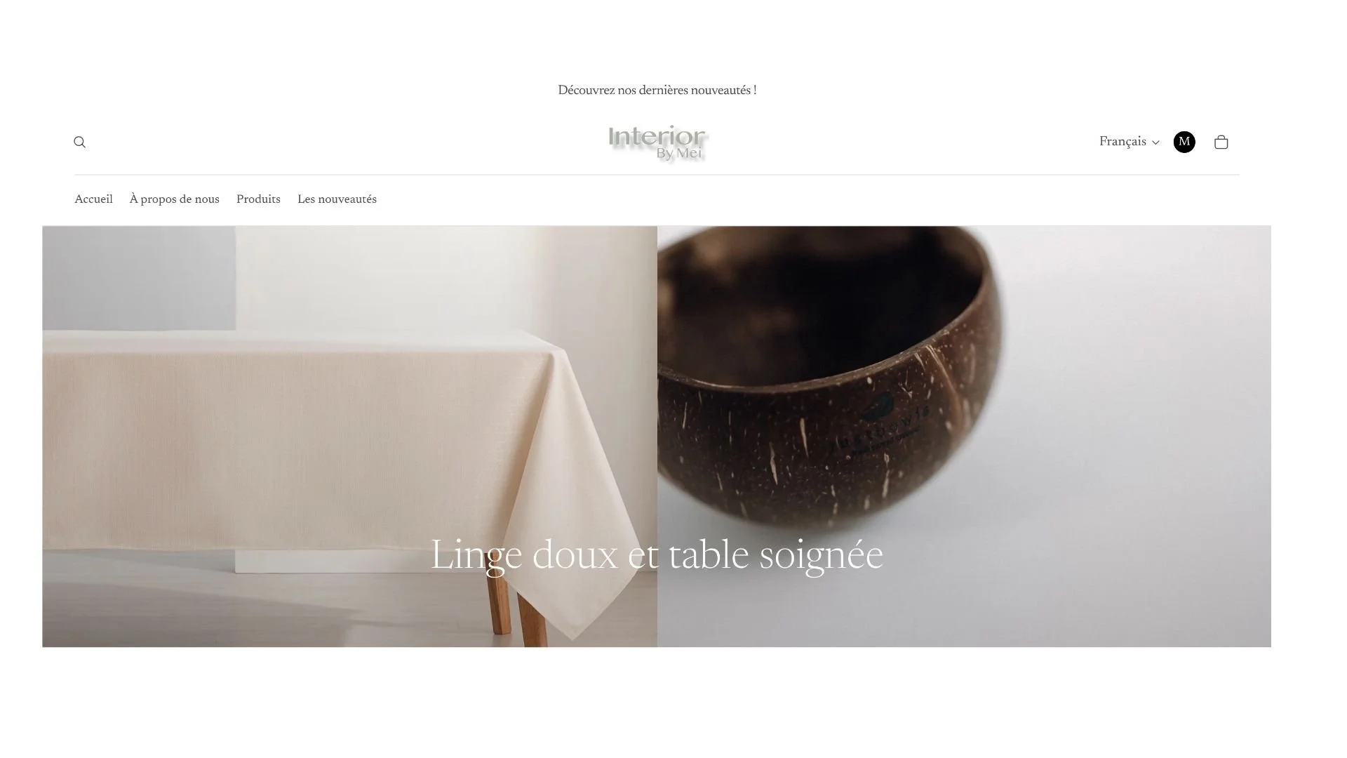 Page d'accueil d'un site web de décoration intérieure avec un en-tête simple, un menu de navigation, un logo centrée et une grande image montrant une nappe beige sur une table et un bol en coquillage en bois, avec un texte flottant indiquant « Linge 