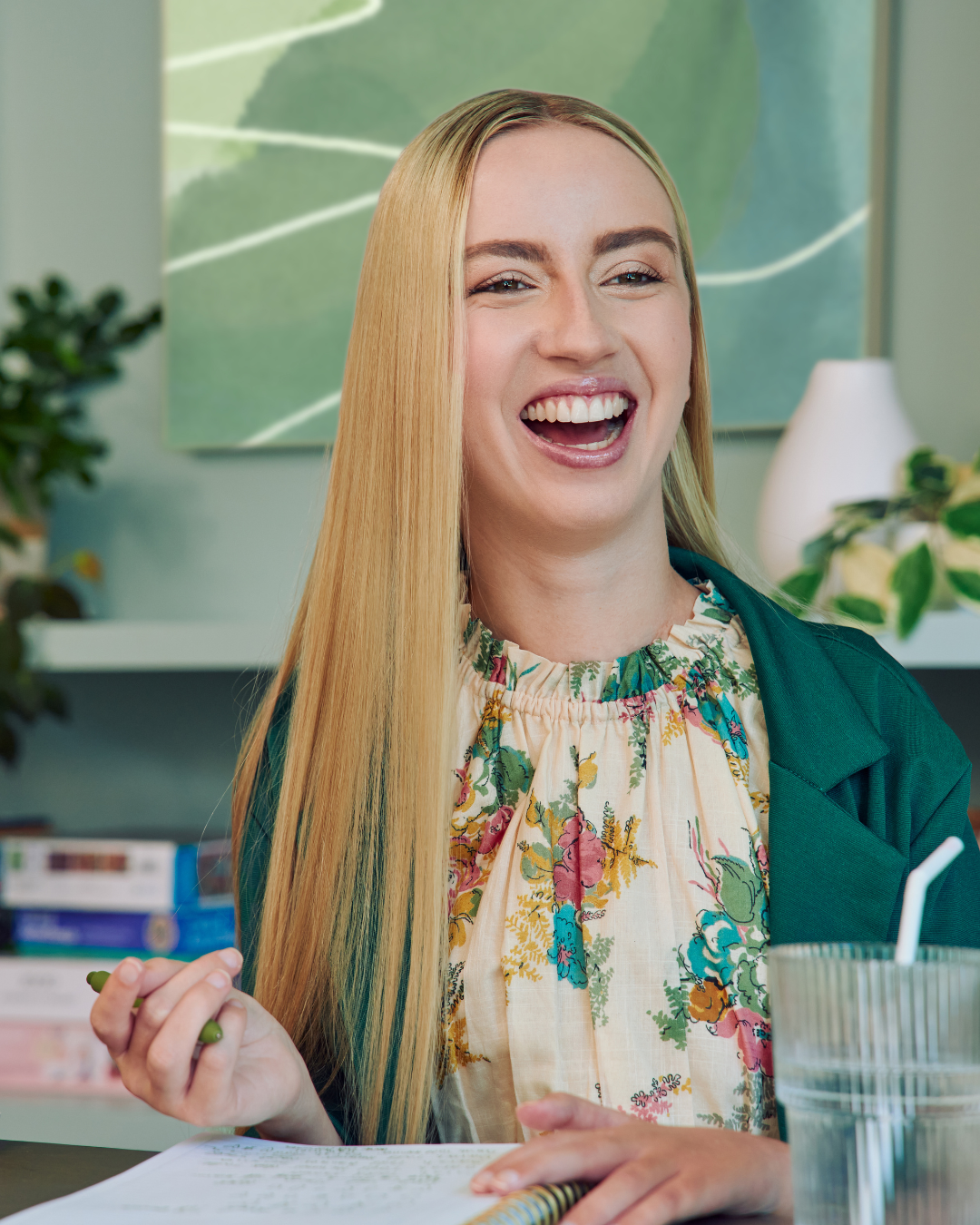 White woman smiles at her peer past the camera. She wears a beige blouse with flowers, and has a mobility impairment