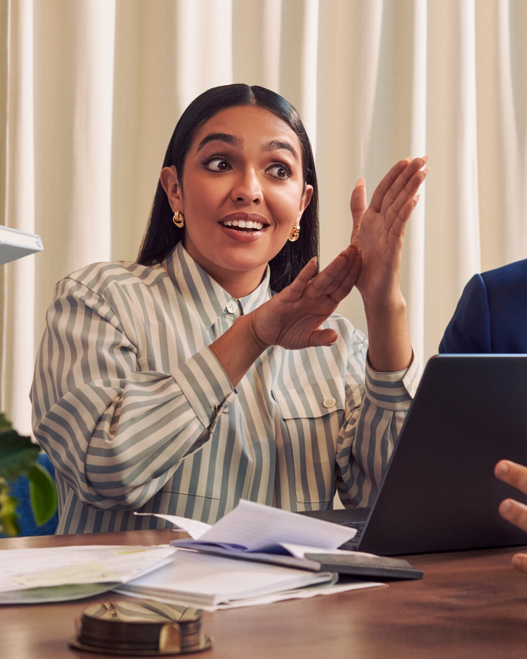 A Deaf Latina woman communicates in American Sign Language to colleagues in a conference room meeting.