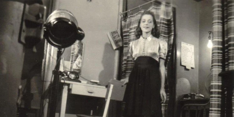 A black-and-white photograph of civil rights leader Viola Desmond standing inside her Halifax business, Viola's Studio of Beauty Culture, opened in 1937