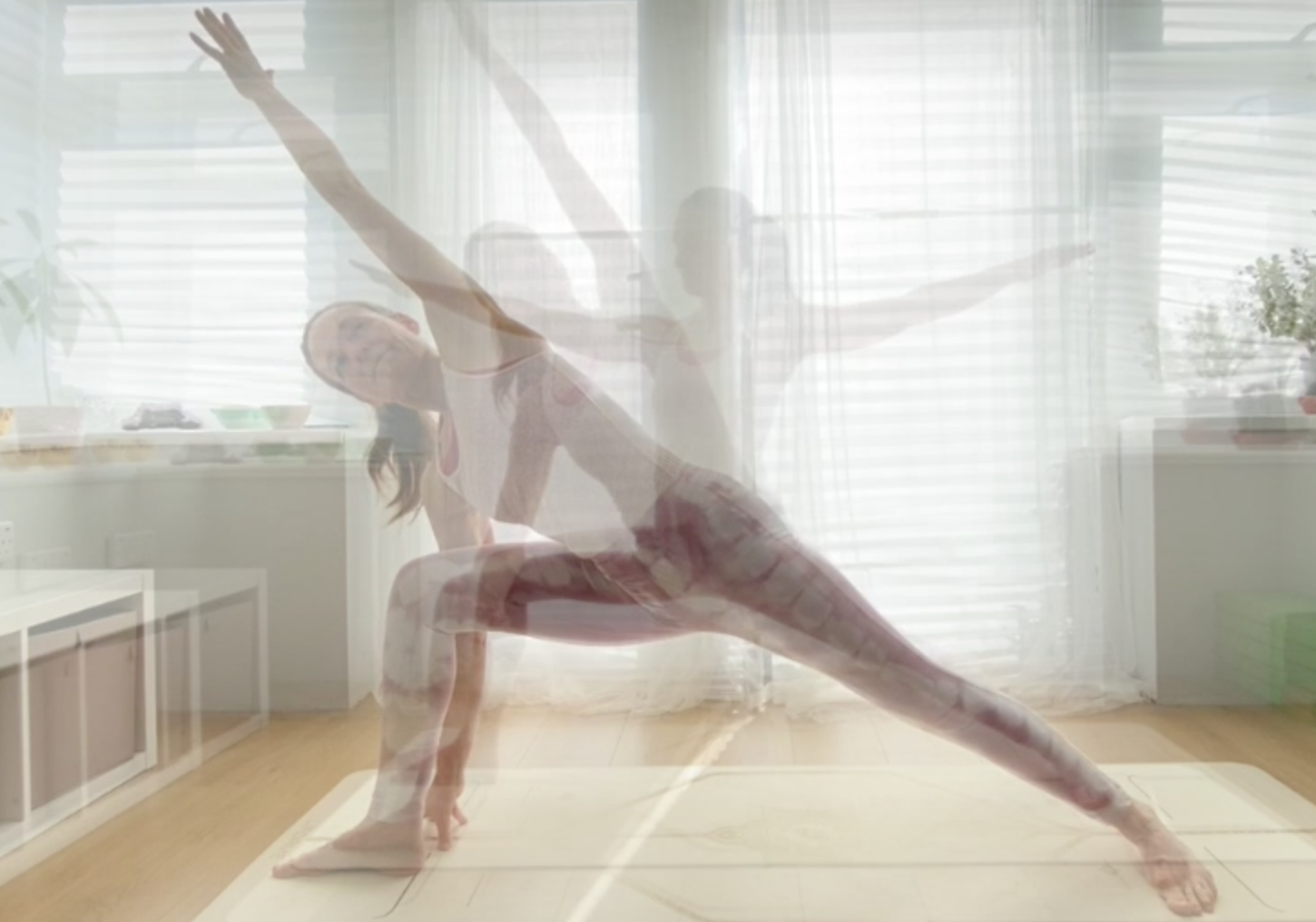 A person practicing yoga indoors, performing a side plank with an extended arm, with a reflection showing multiple poses against sheer curtains and a bright room.