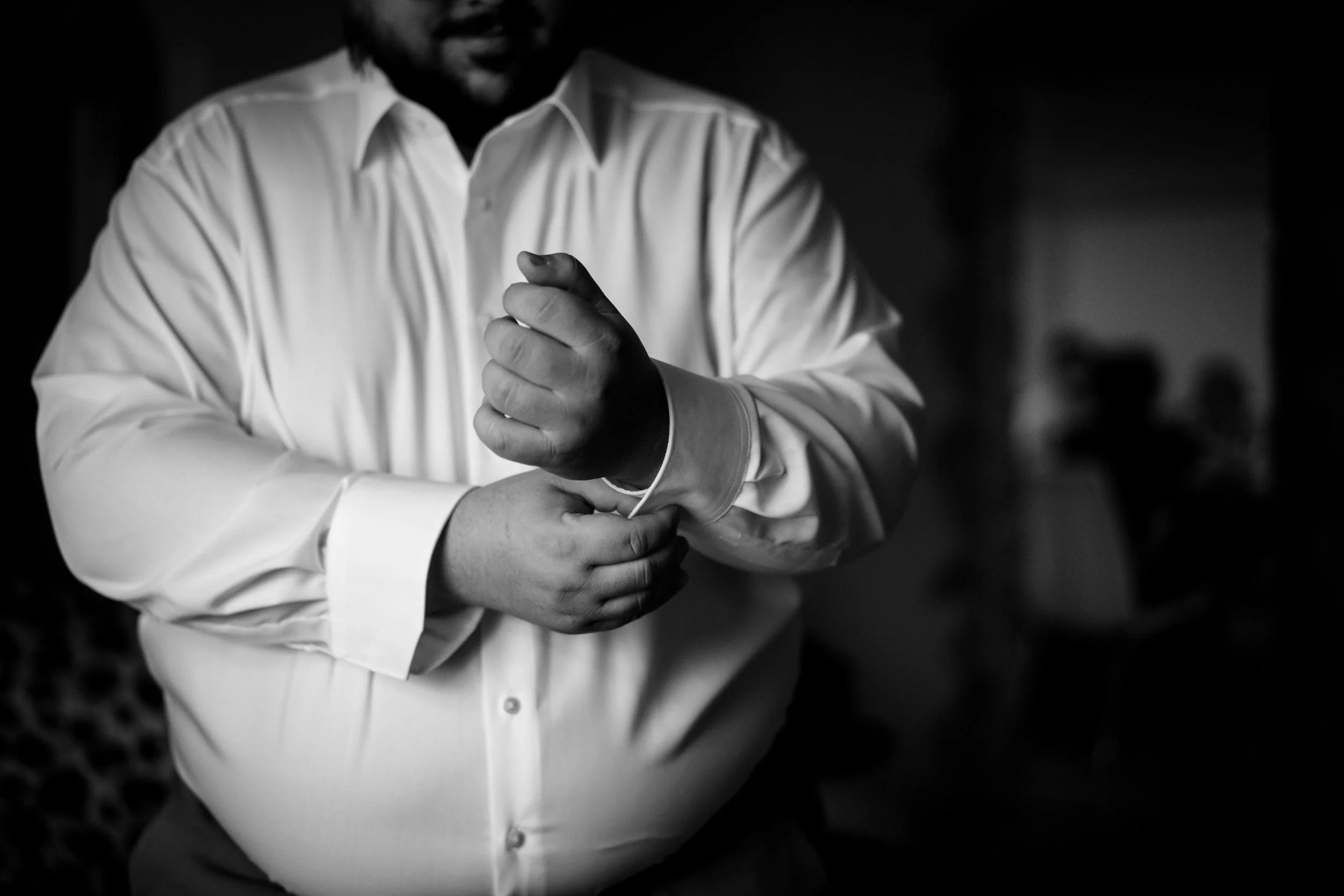 A man buttoning his white dress shirt.