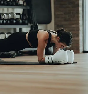 Woman doing a plank exercise with her forearms on the floor in a gym.