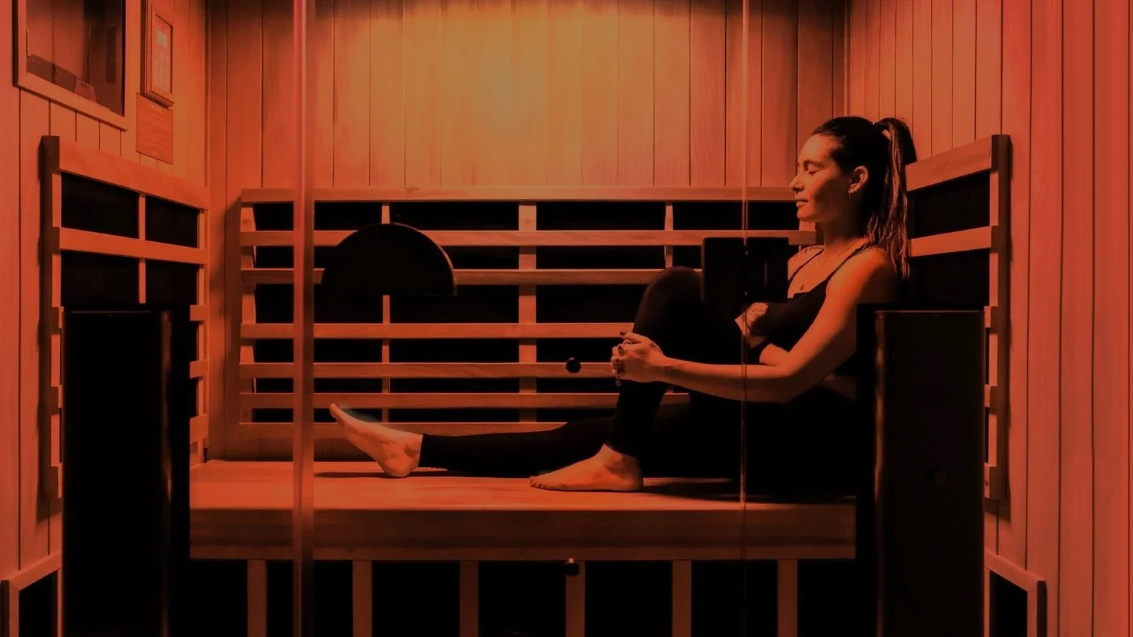 A woman relaxing in a luxury private infrared sauna suite at REVIVAL Wellness.