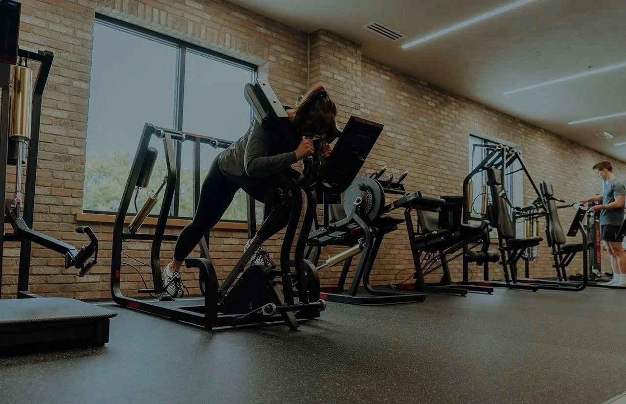 Woman using the Keiser Performance Circuit equipment with other exercise equipment in the background.
