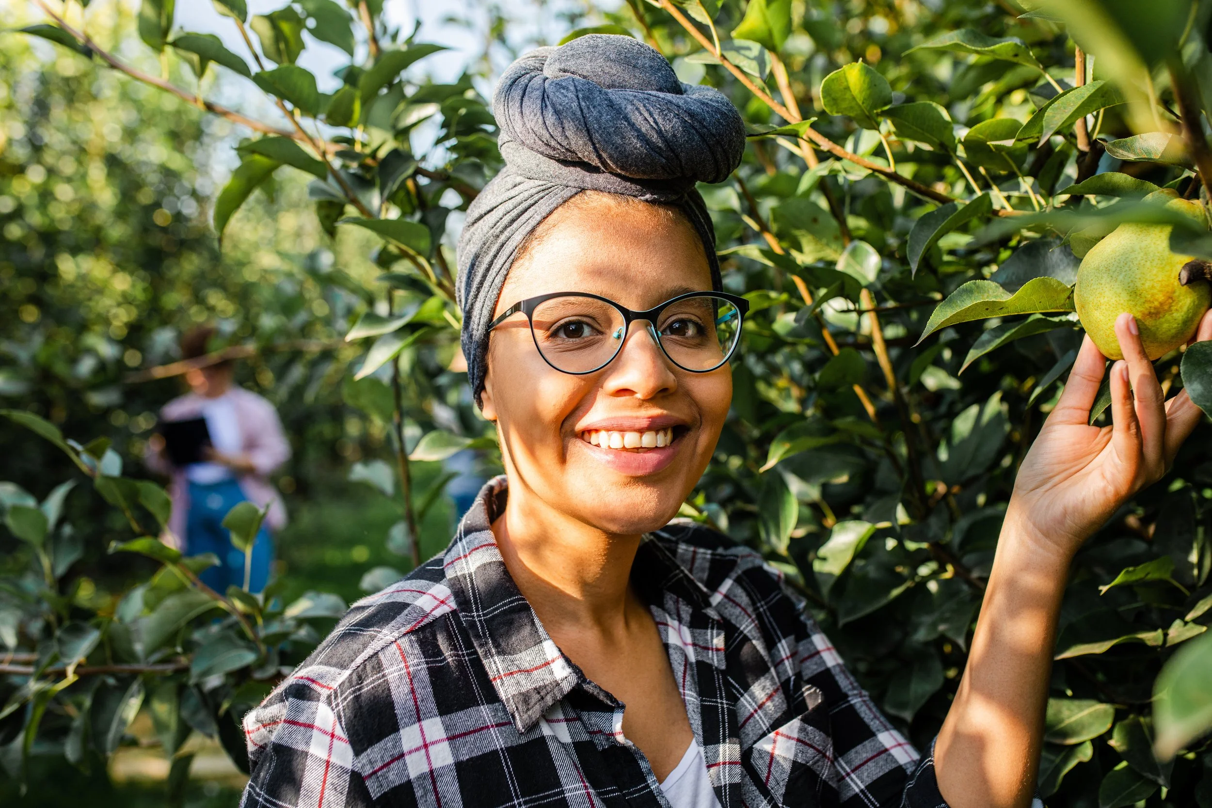 Smiling female farmer examining fresh fruit in an orchard.
