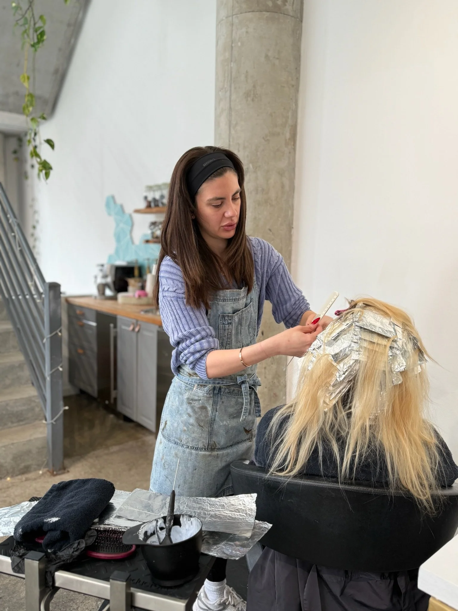 stylist applying bright blonde highlights at Gem House Salon in Greenpoint Brooklyn professional hair color service NYC