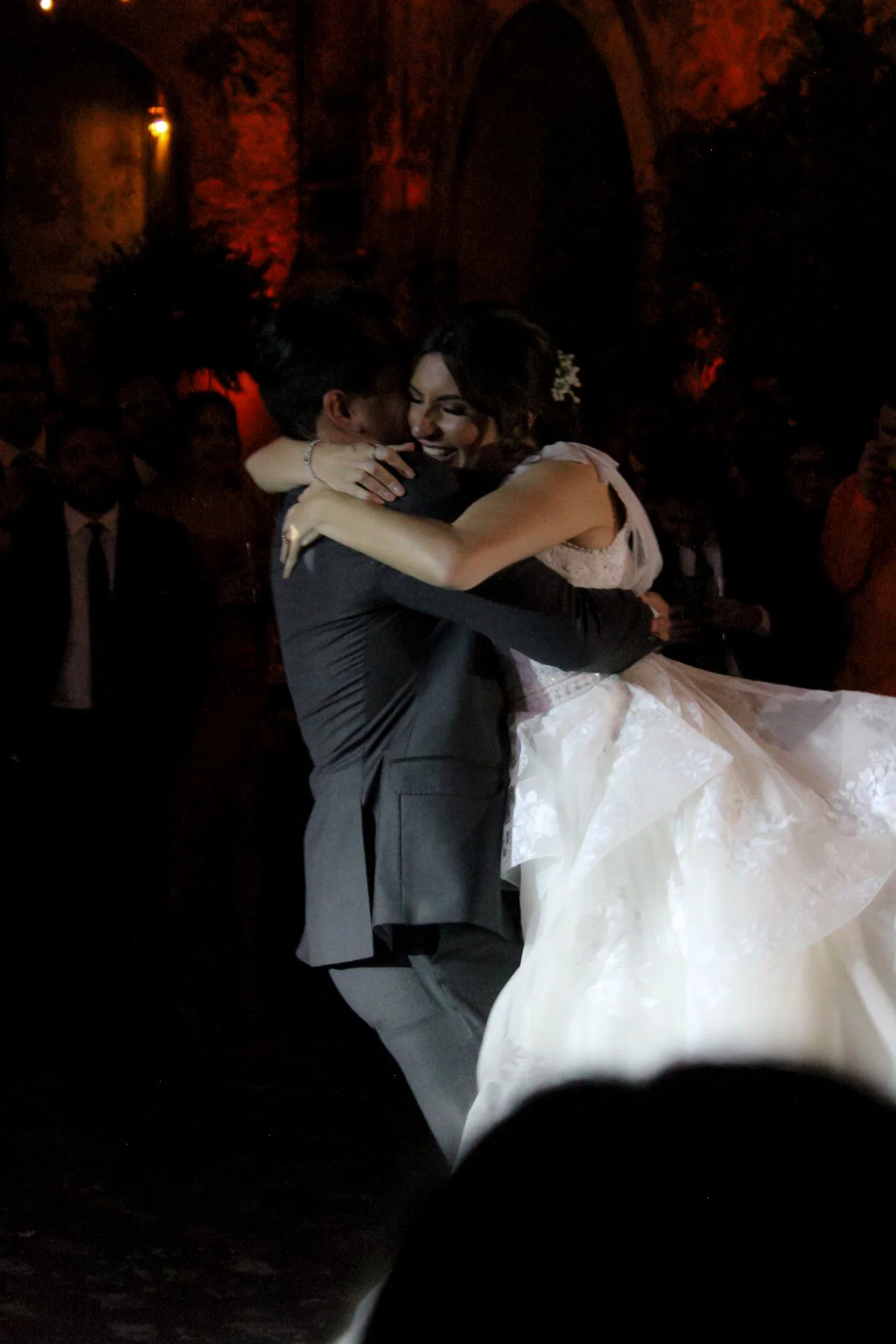 Pareja de recién casados bailando en una boda, ella sonríe y él la sostiene en un abrazo.