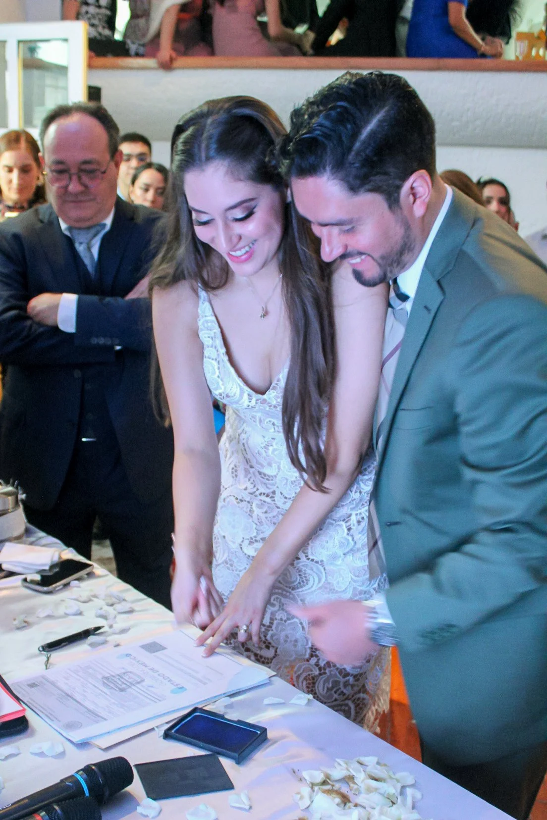 Pareja en vestido y traje firmando un documento en una ceremonia.