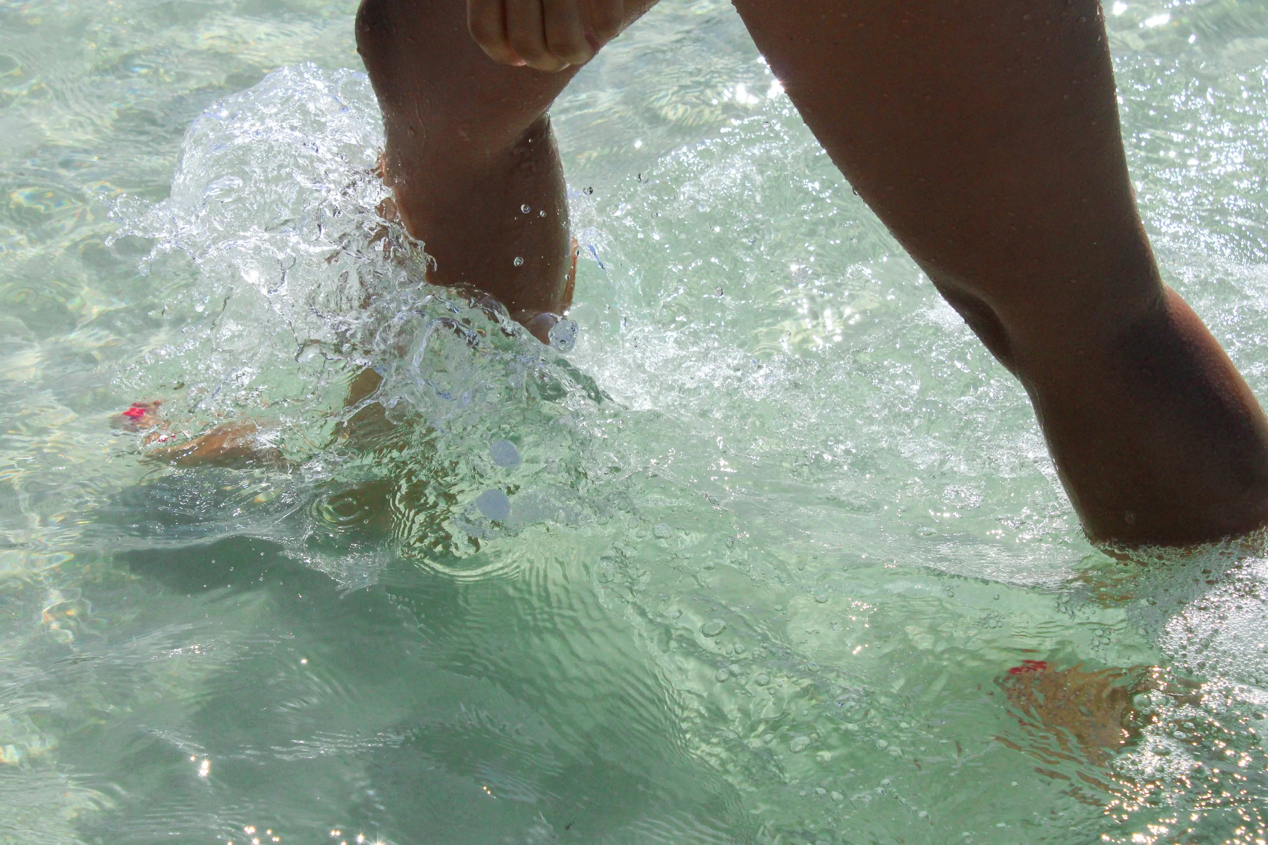 Persona nadando en agua clara con movimientos y salpicaduras