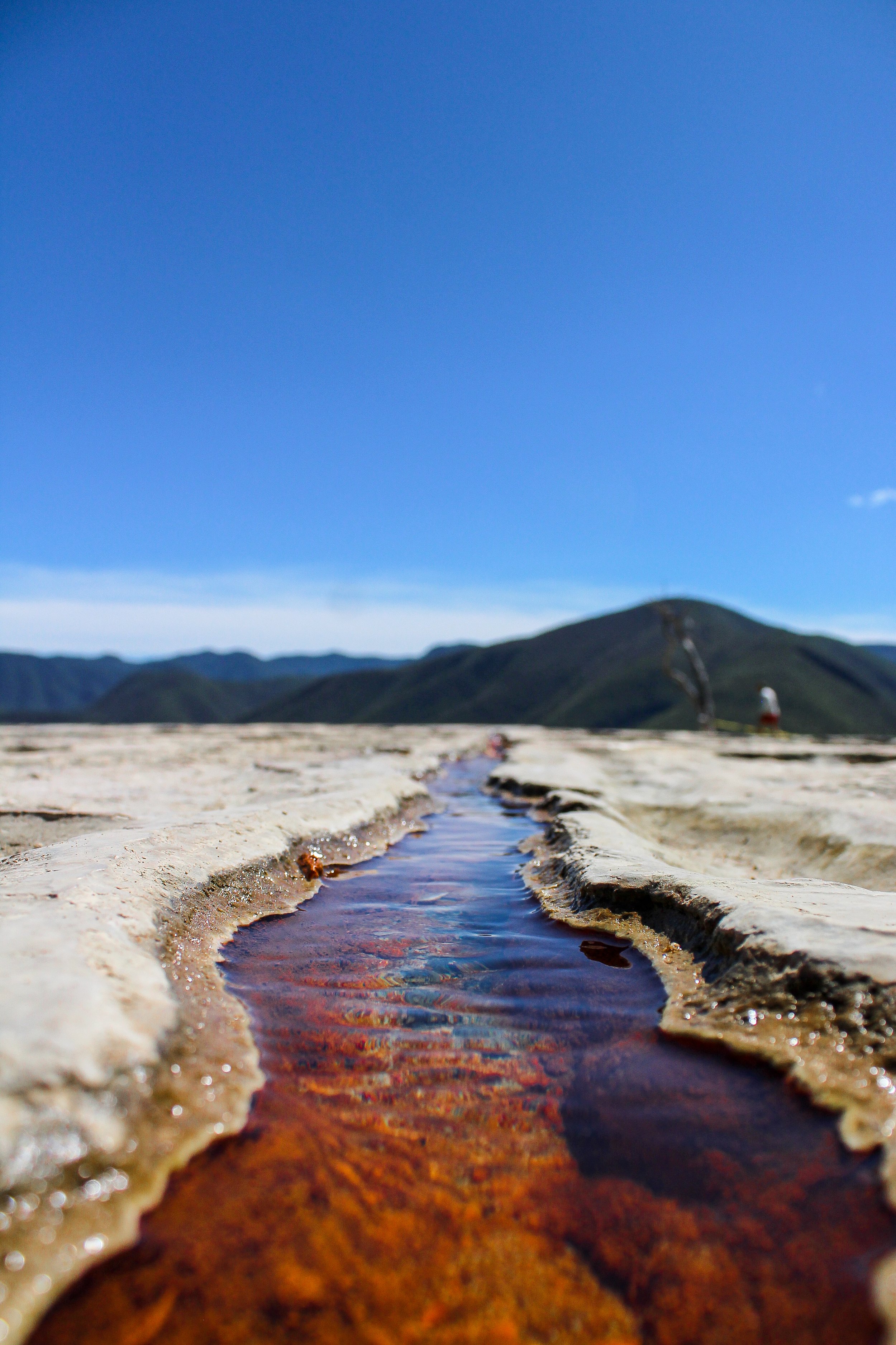 Un río de agua cristalina en un paisaje montañoso con un cielo azul claro