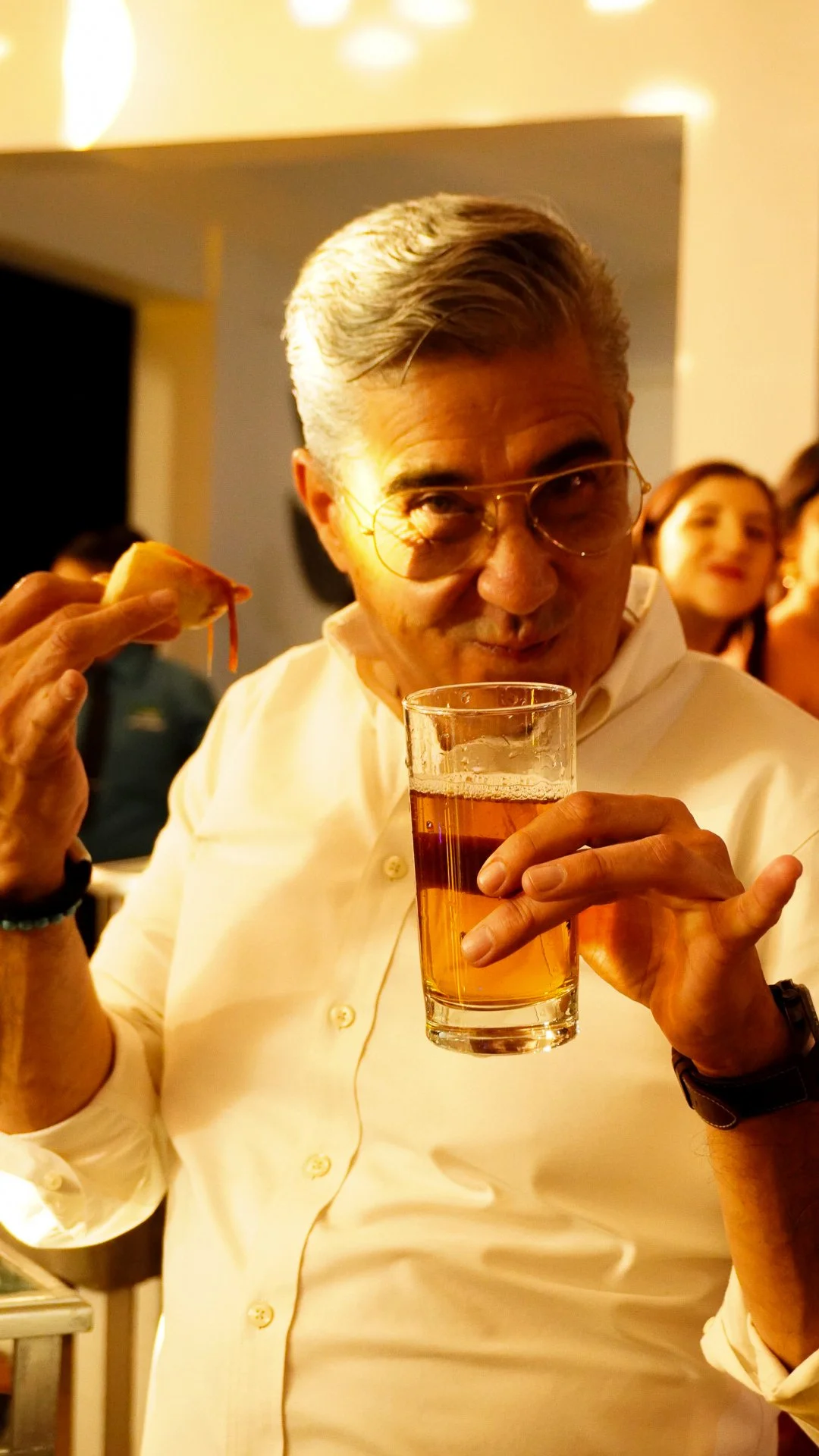 Hombre con gafas bebiendo una cerveza en una fiesta.