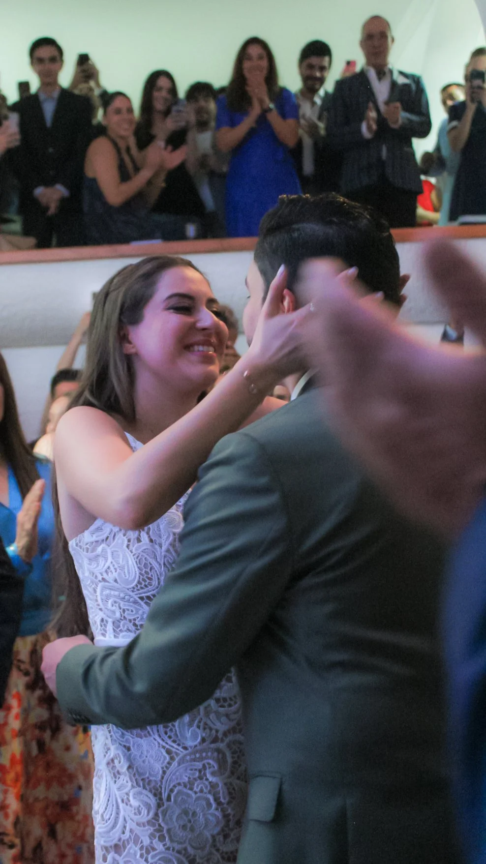 Pareja bailando en una boda, rodeada de amigos que los observan y toman fotos.