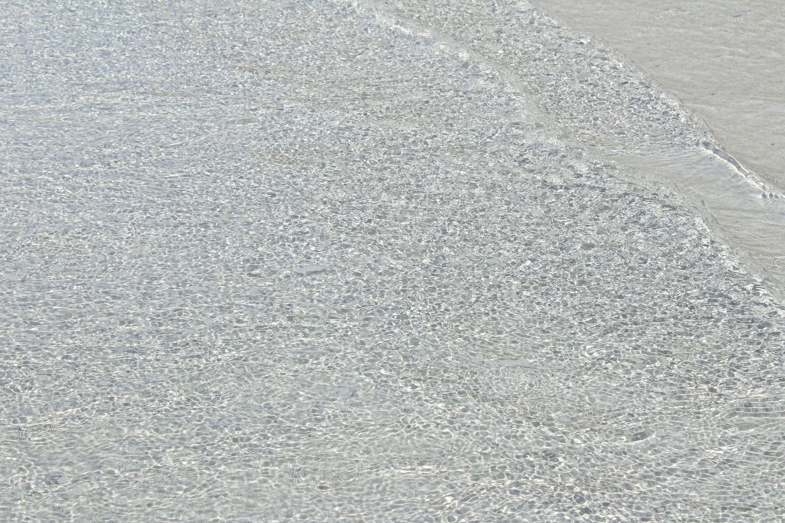 Olas suaves en una playa de arena blanca con agua cristalina y transparente.
