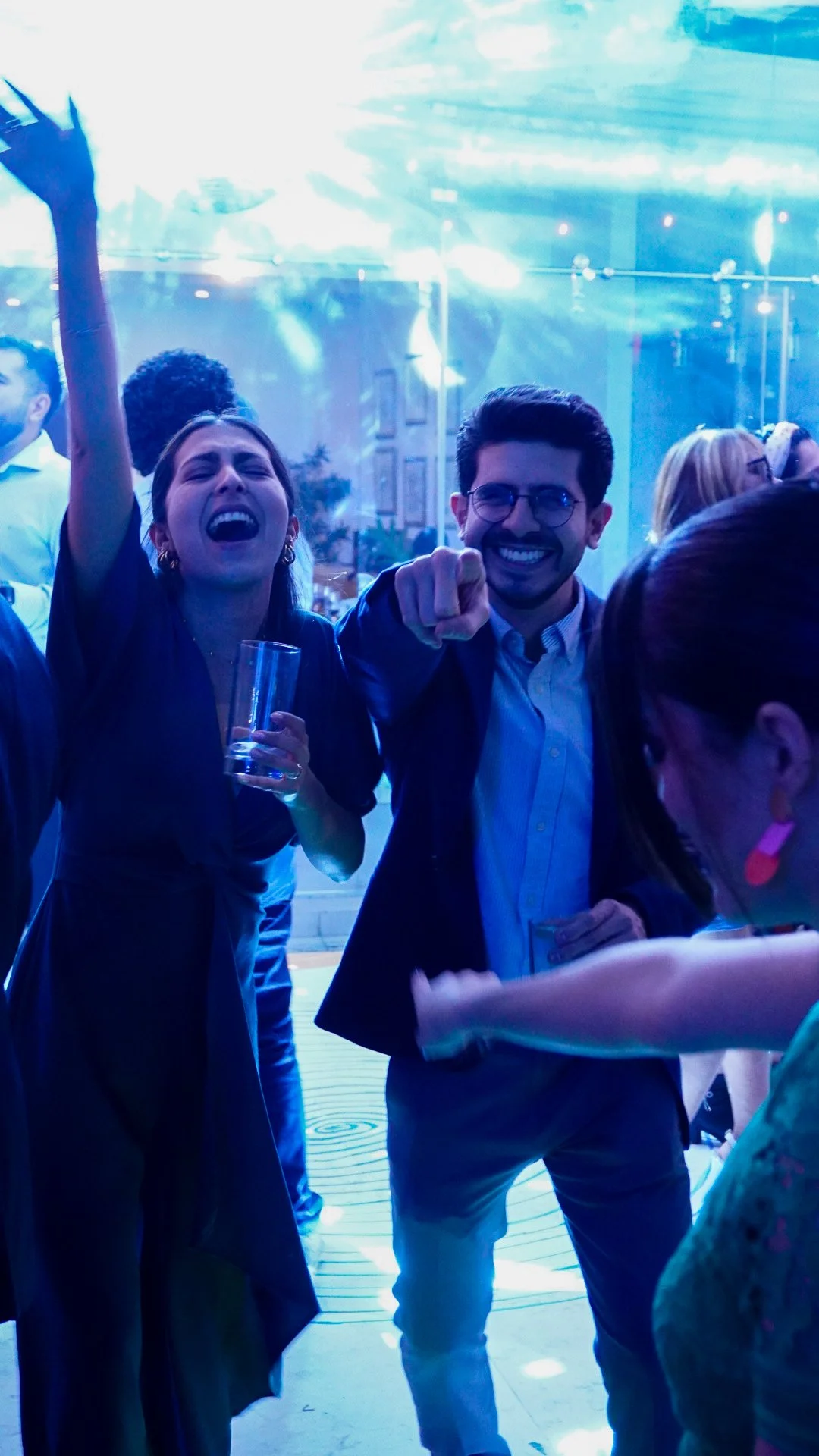 Personas disfrutando en una fiesta, una mujer con expresión emocionada y un hombre sonriendo y señalando.