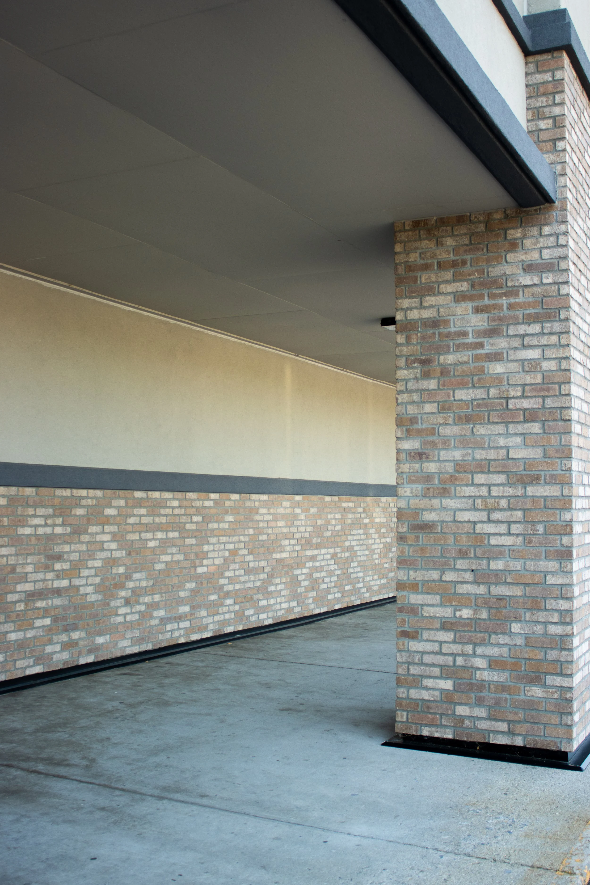 Photo of brick columns and a wall on a sidewalk near a building.