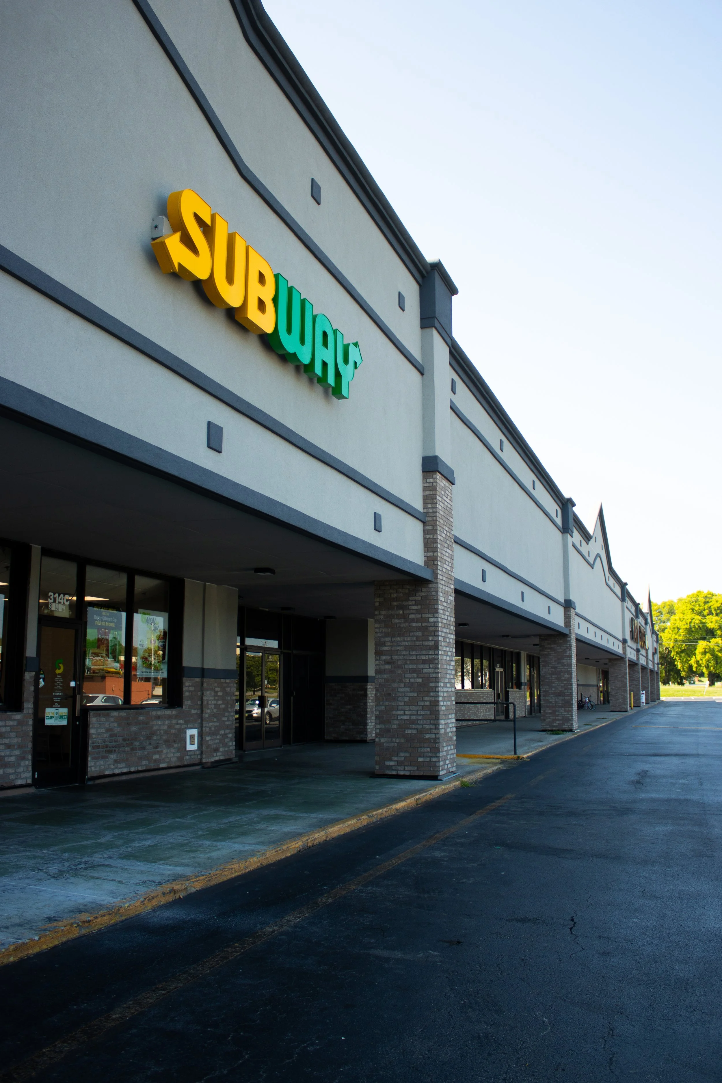 Exterior view of a Subway restaurant with its sign on the building, located in a strip mall.