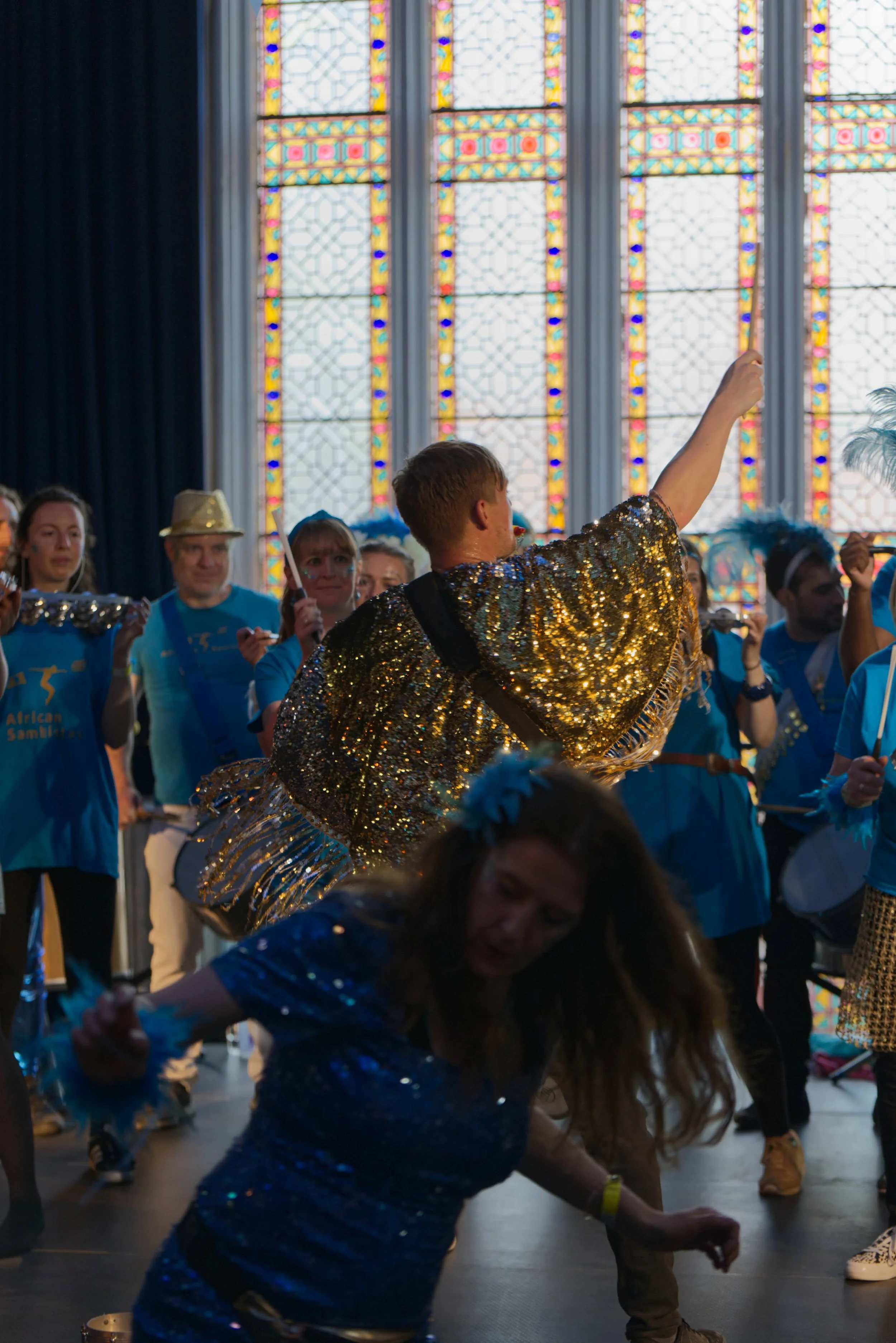 People dressed in colorful costumes dancing and celebrating inside a church with stained glass windows.