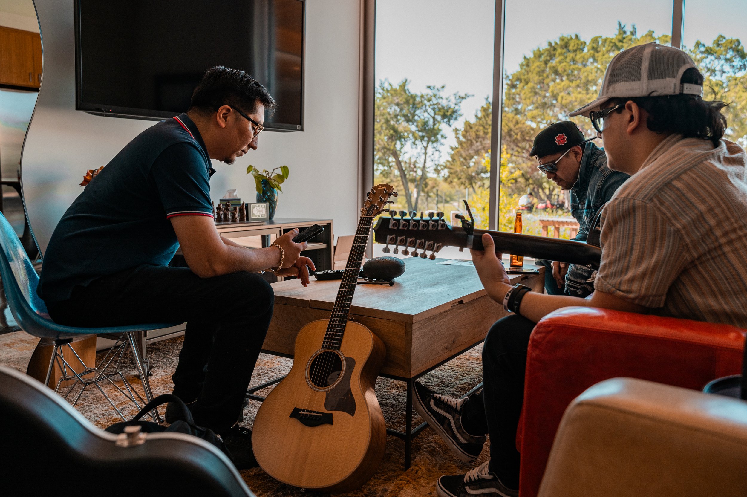 Three men sitting inside in Firefly Sound Studio during a Studios at Fischer writing retreat