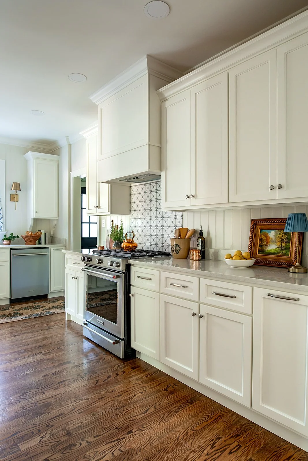 Warm white kitchen with a custom vent hood and restored hardwood floors
