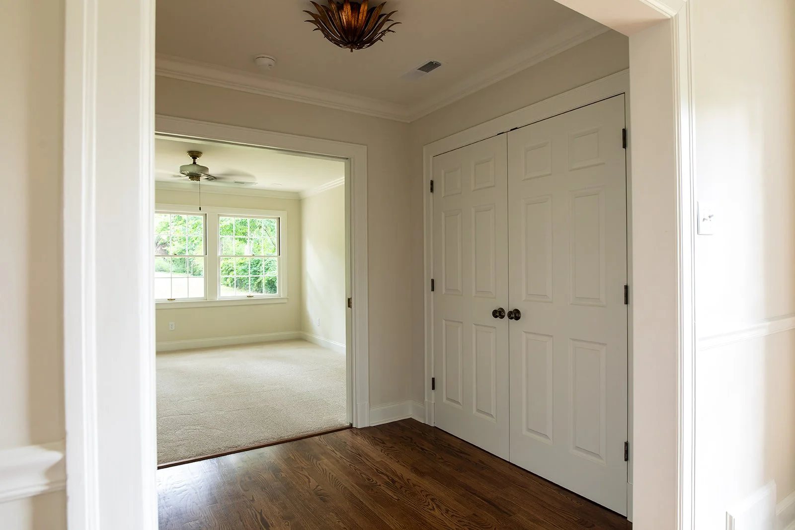  Hallway with refinished oak floors, white paneled doors and a gold ginkgo-leaf semi-flush ceiling light. 