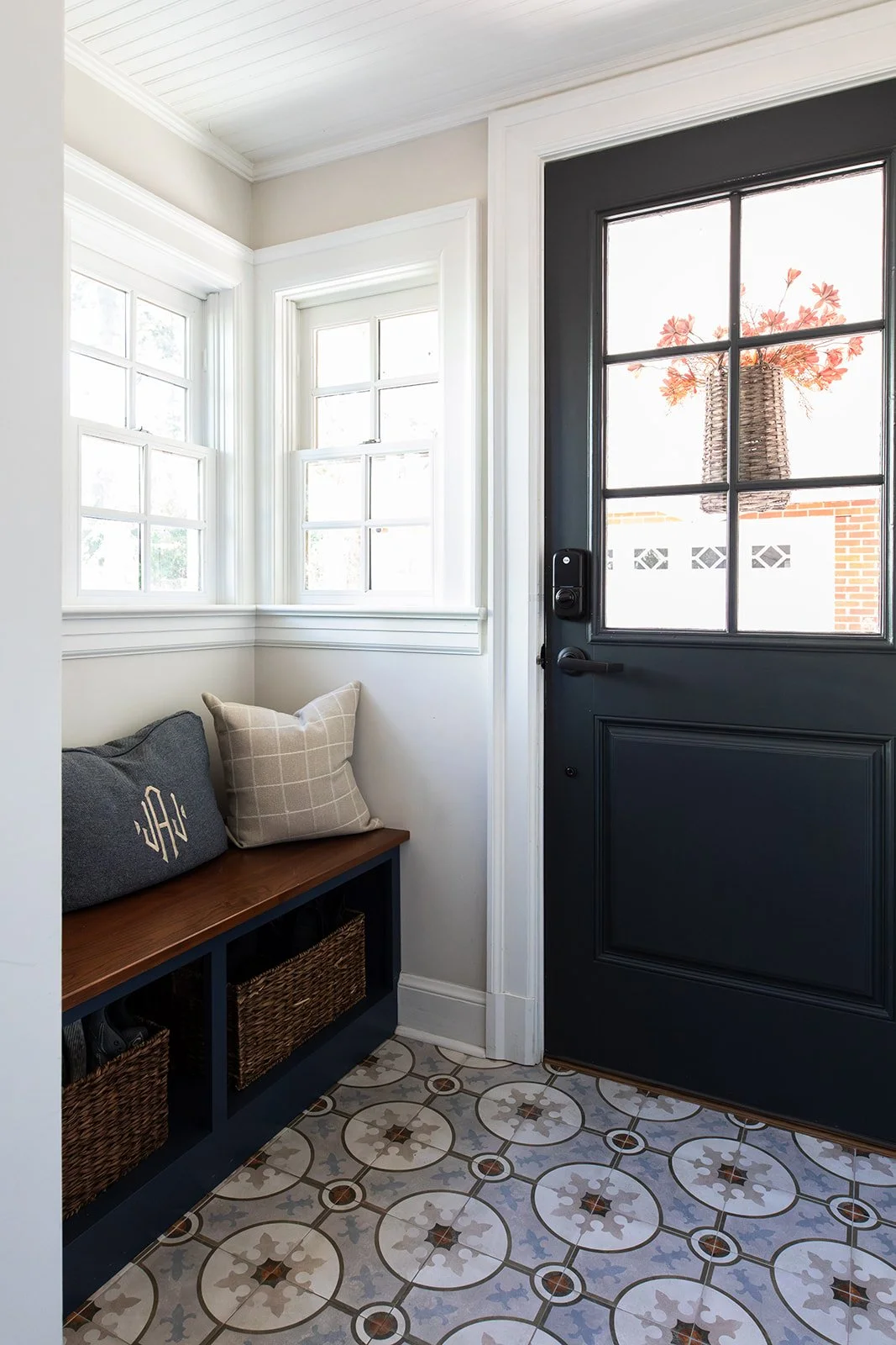 Back entry with a navy door, built-in bench, and patterned cement tile floor
