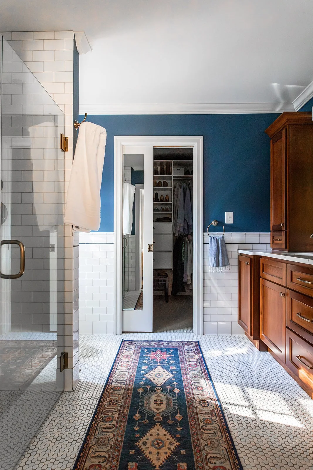 Primary bath with a view through to the closet and a patterned runner