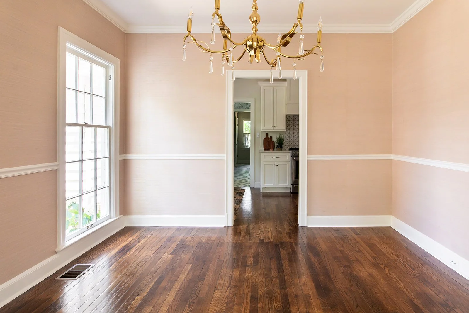 Formal dining room in blush grasscloth under a gold chandelier