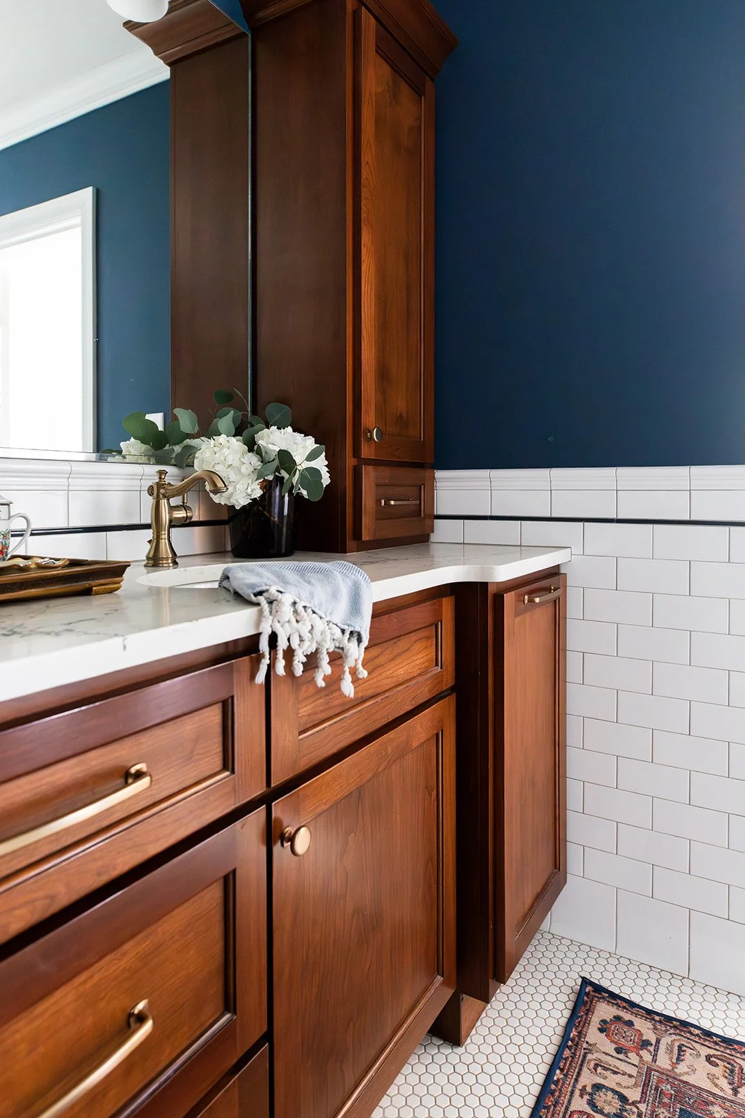 Cherry vanity with subway-tile wainscoting and a folded hand towel