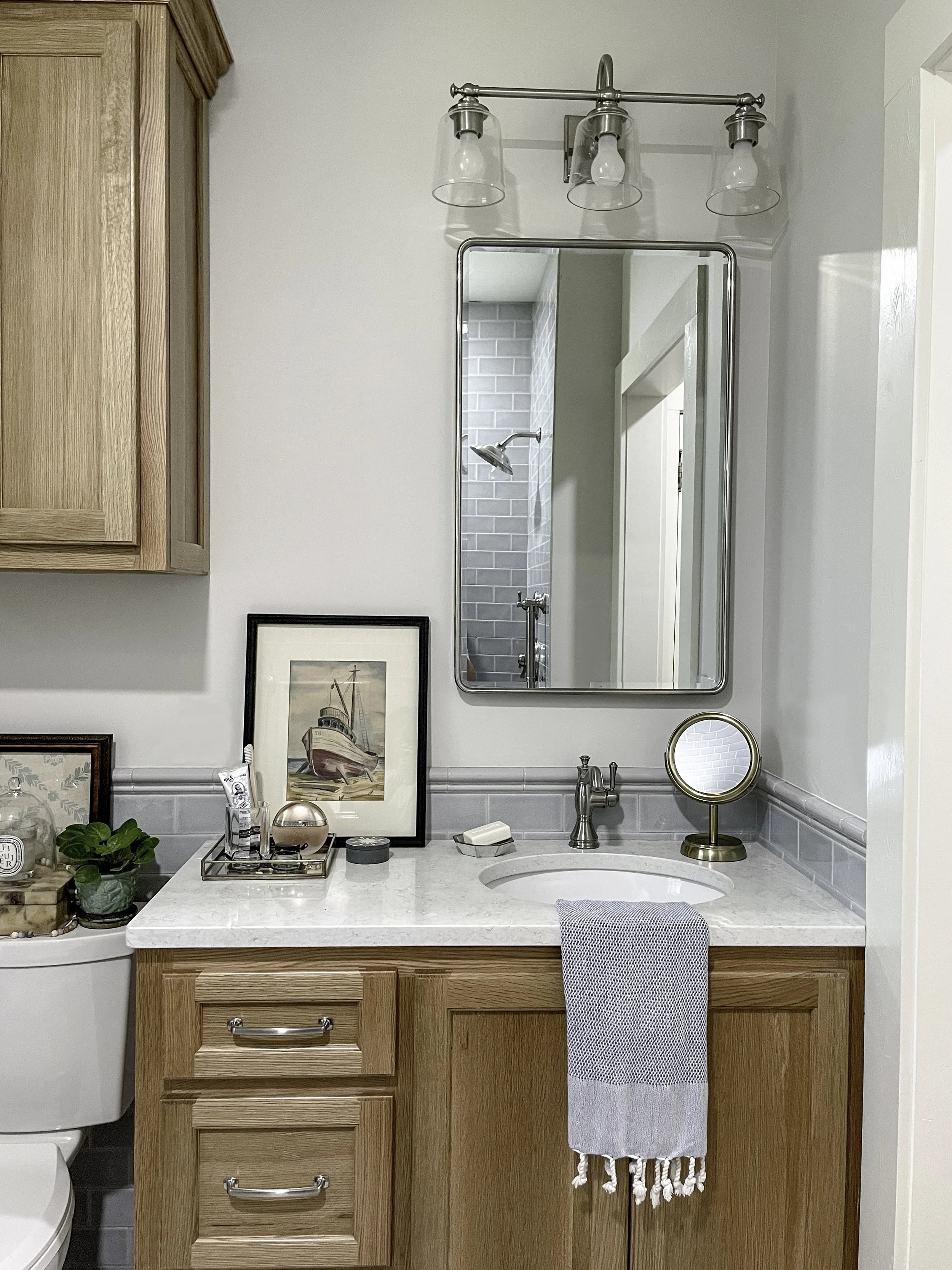 Wood vanity with a framed mirror, chrome faucet, and a gray hand towel