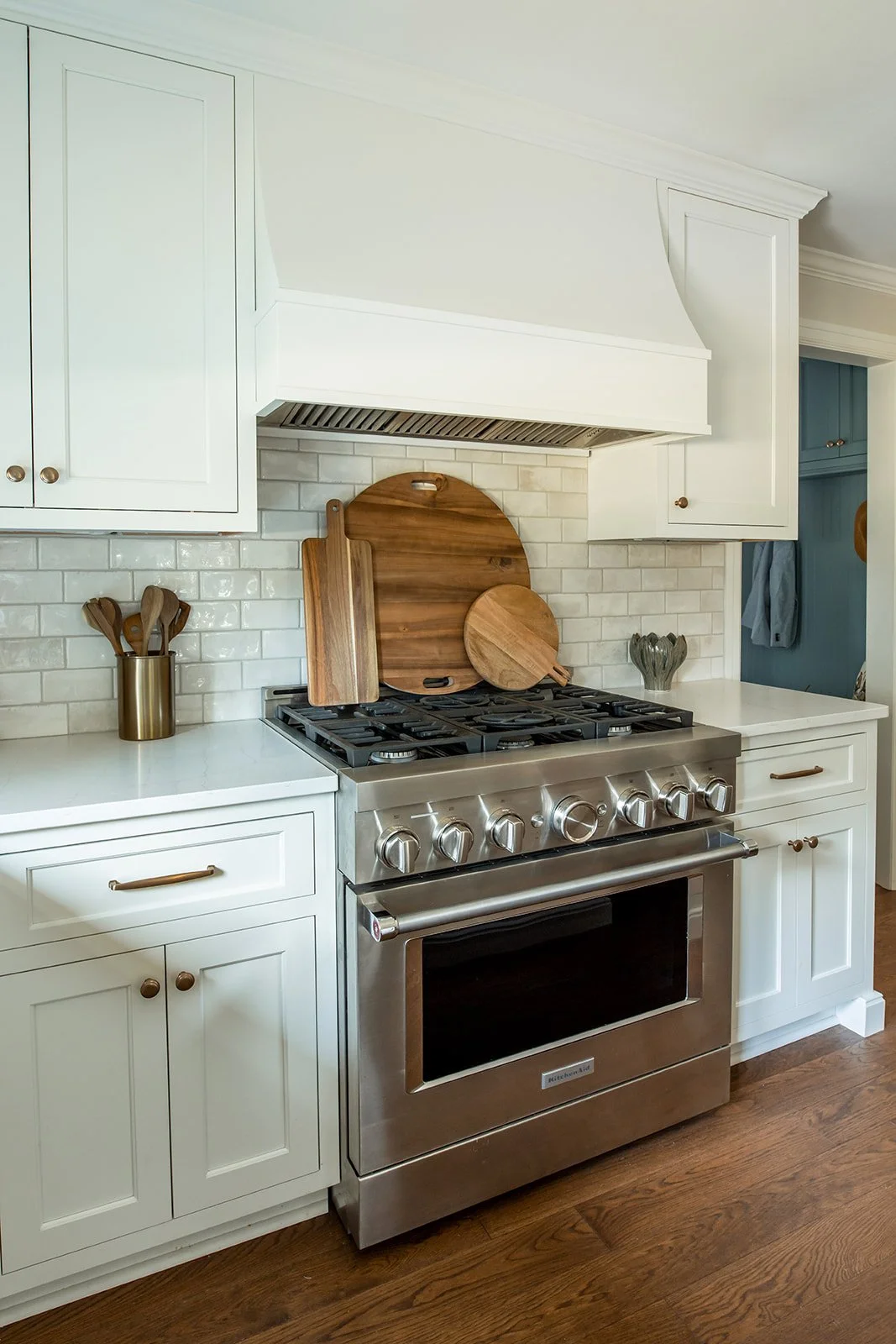 Custom wood vent hood over a stainless range with subway tile