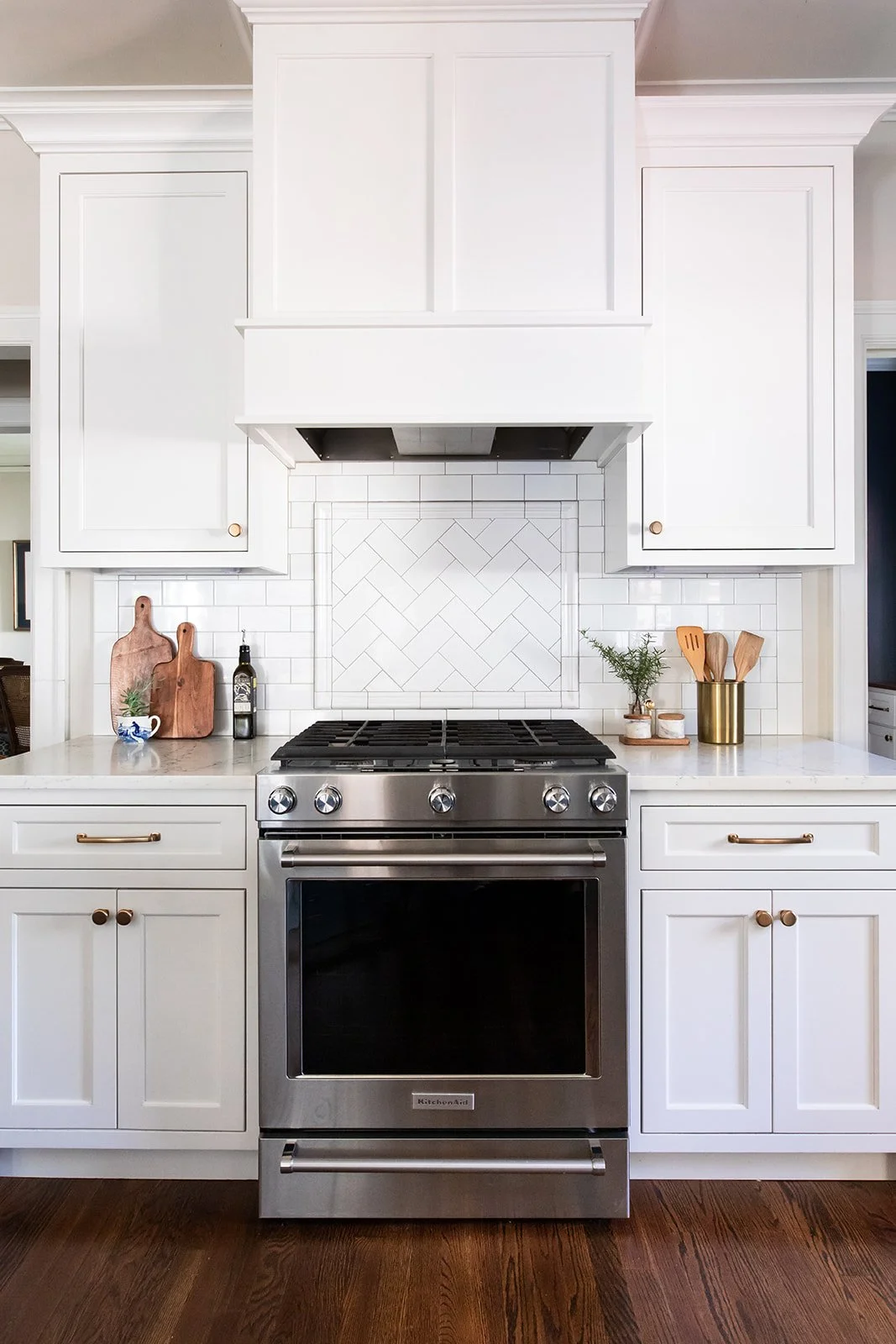 Slide-in range framed by white cabinetry and a herringbone backsplash