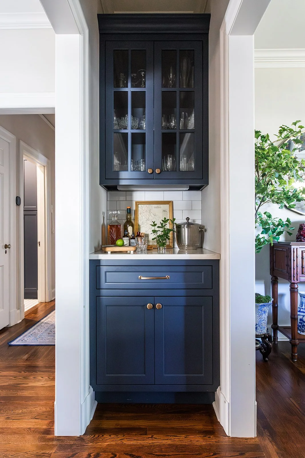 Navy glass-front bar cabinet with a quartz counter in a butler's pantry