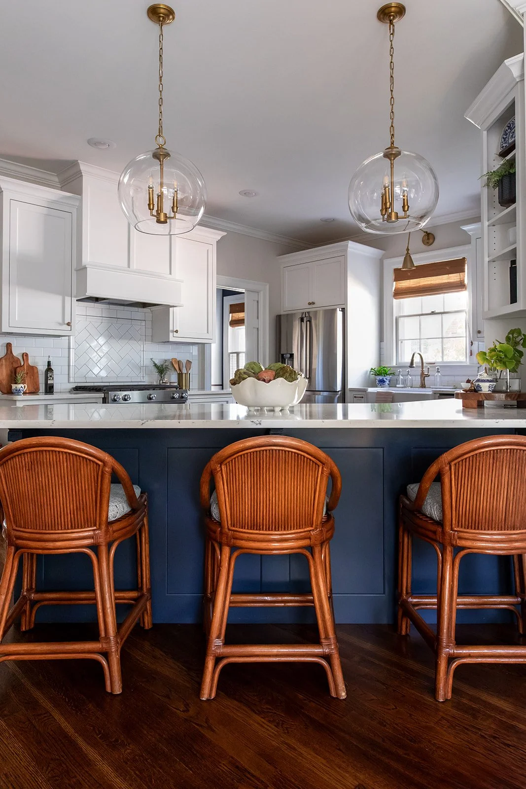 Close view of the navy island with brass globe pendants and woven barstools
