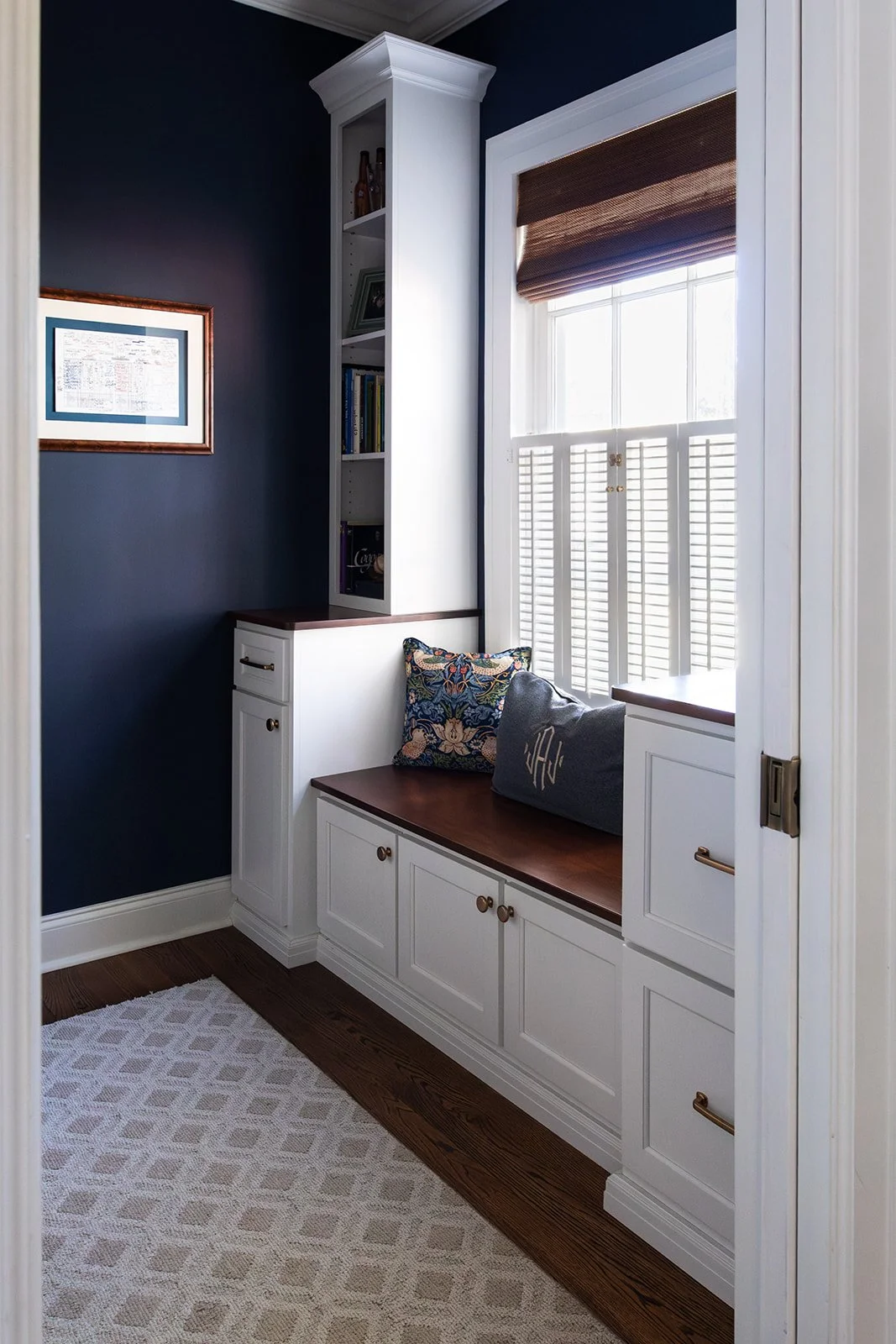 Navy built-in window seat with storage and a patterned rug in a cozy nook