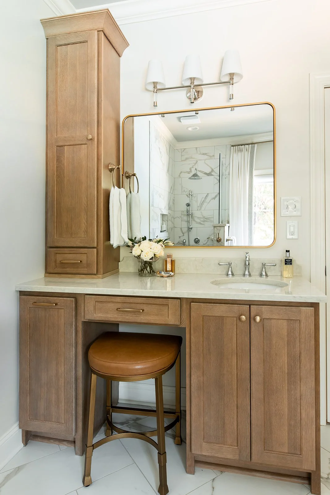Wood vanity with a makeup counter, stool, and a brass-framed mirror