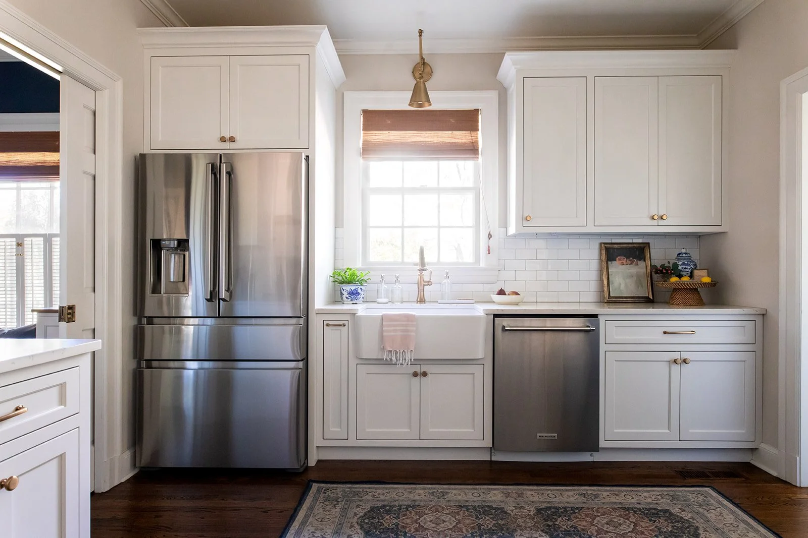 Kitchen with a stainless refrigerator, white cabinets, and a runner rug over hardwood floors