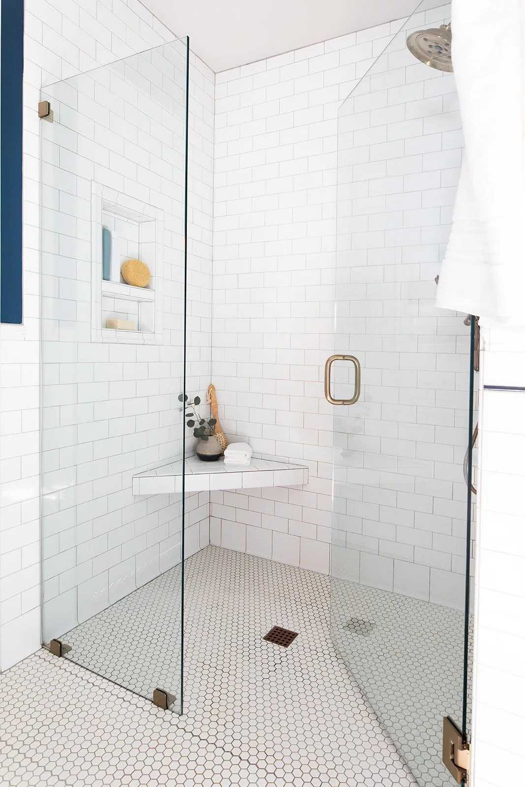 White subway-tile walk-in shower with a corner bench and niche