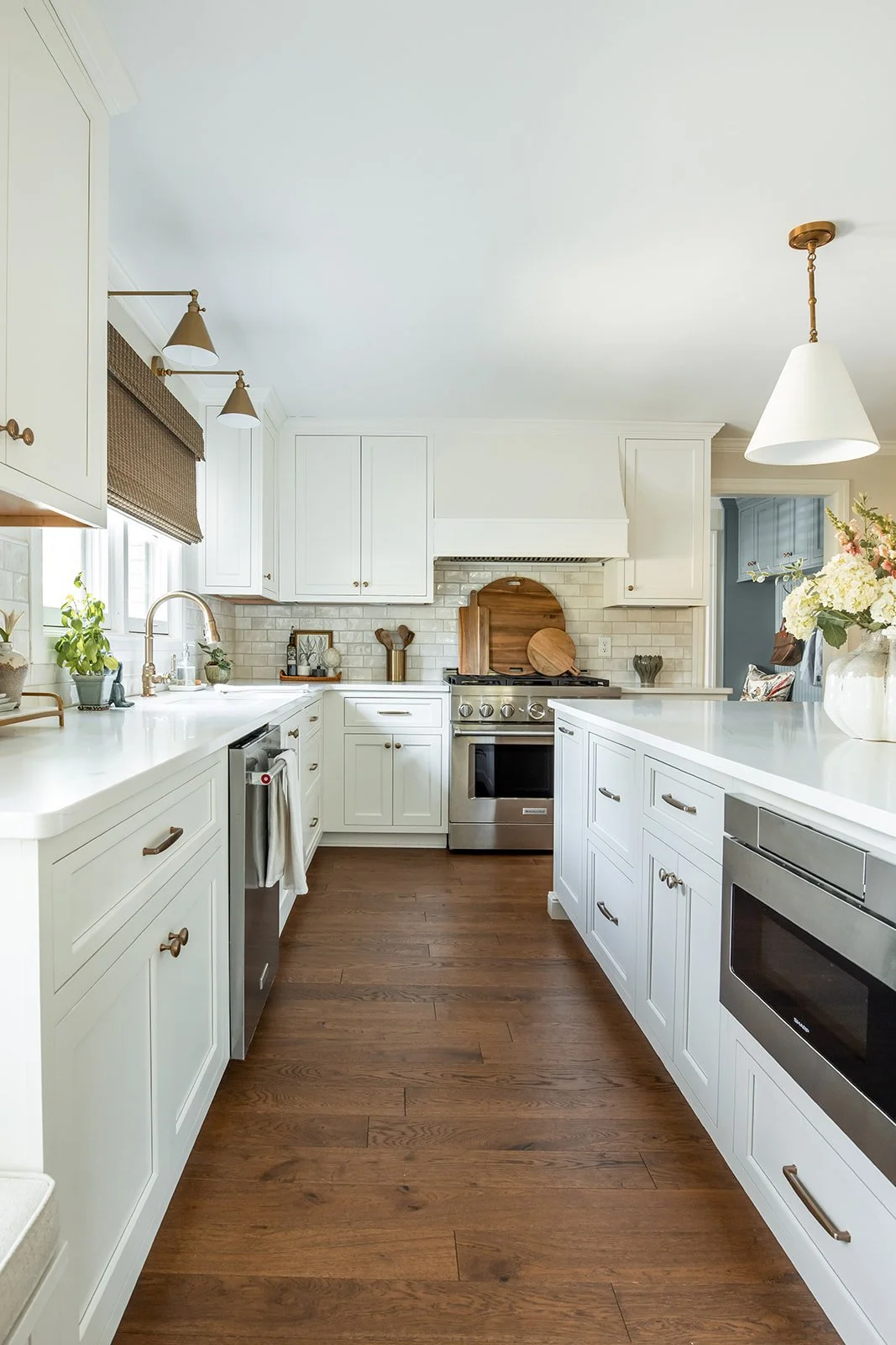 White kitchen with a custom hood, range, and a microwave built into the island