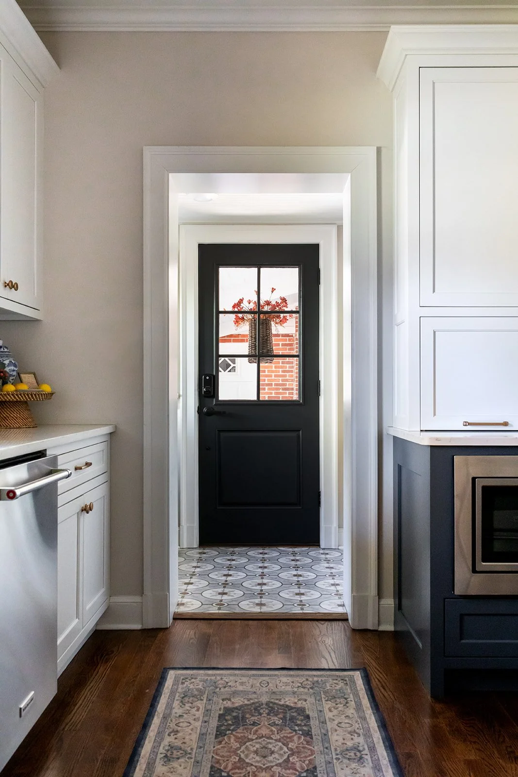 Kitchen hallway leading to a navy multi-pane back door with a patterned runner